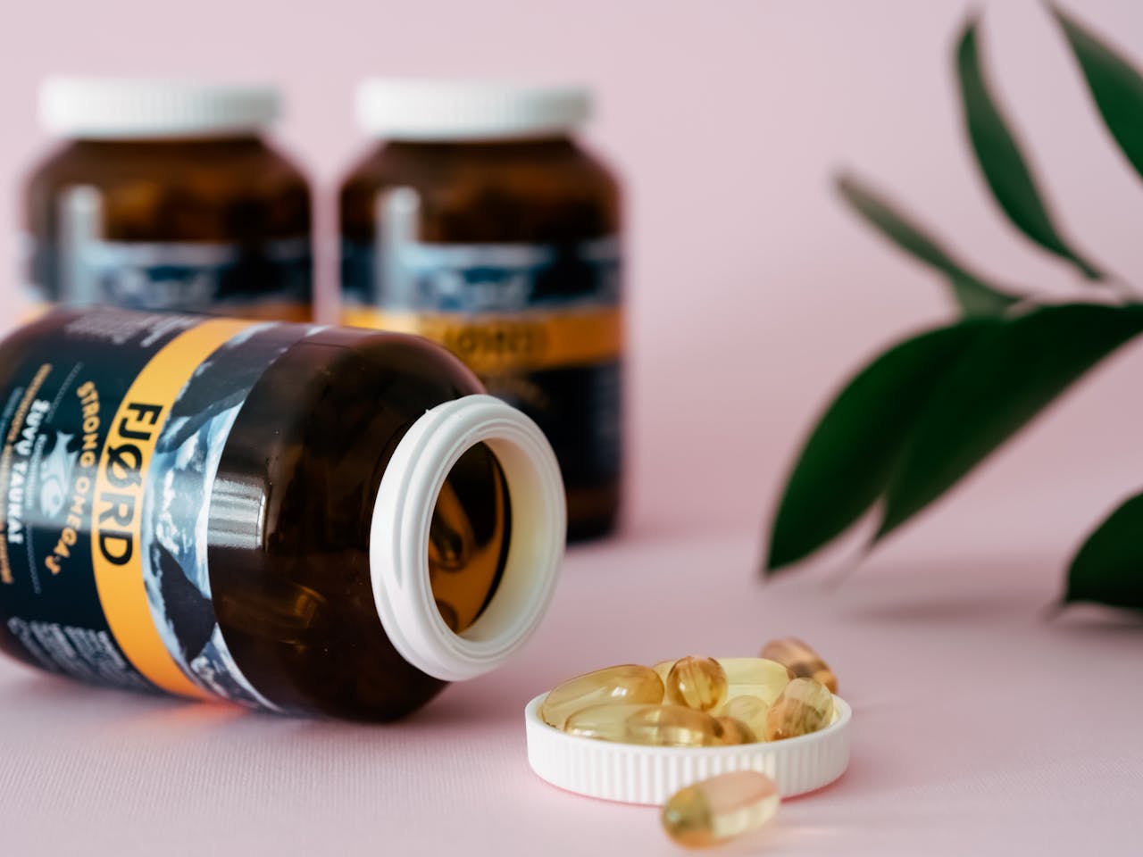 Close-up of omega-3 capsules and bottles on a pink background, ideal for health and wellness themes.