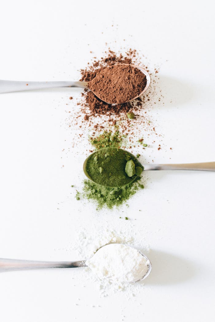 digital-01 Flat lay of spoons with brown, green, and white powders on a white background.