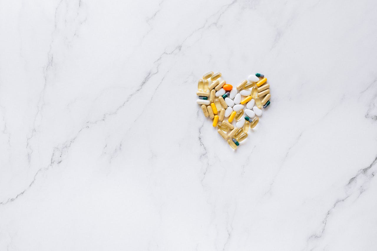 Colorful pills arranged in a heart shape on a marble surface, symbolizing healthcare and well-being.